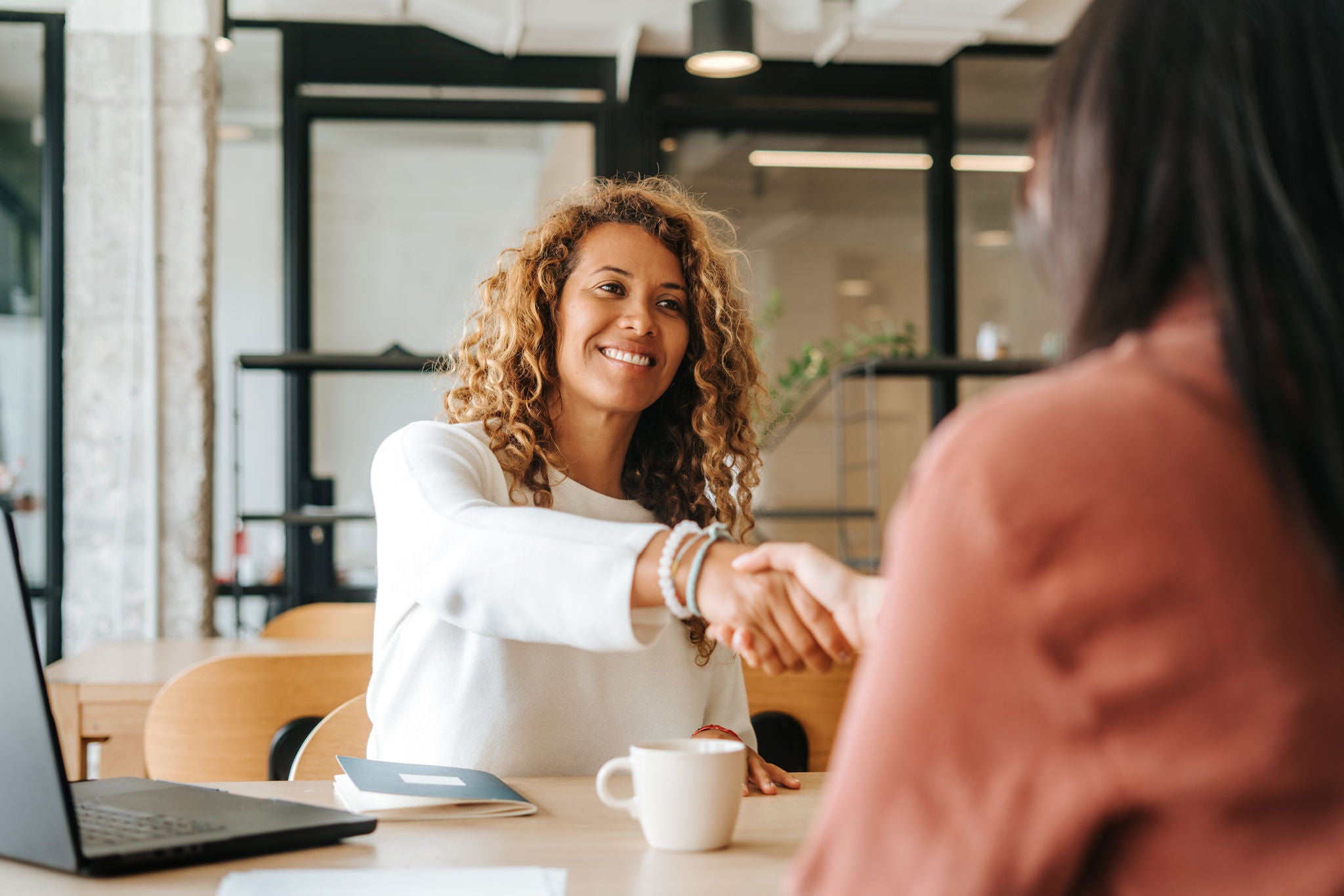 People shaking hands over coffee