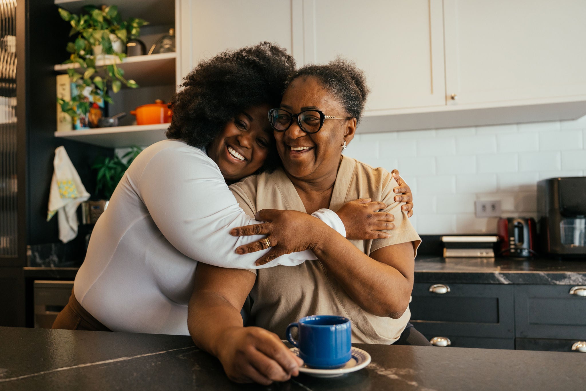 Adult daughter hugging her mother in the kitchen