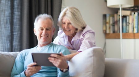 senior couple looking at tablet on couch