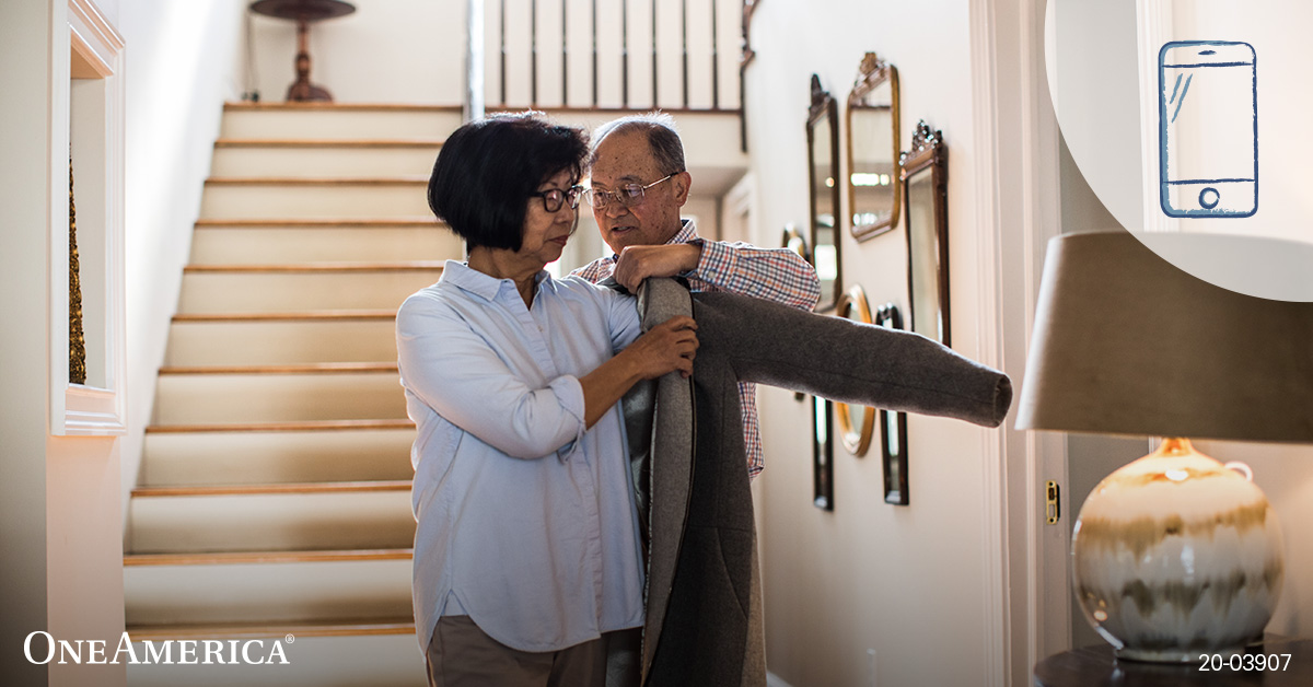 Man helping woman put on jacket inside house